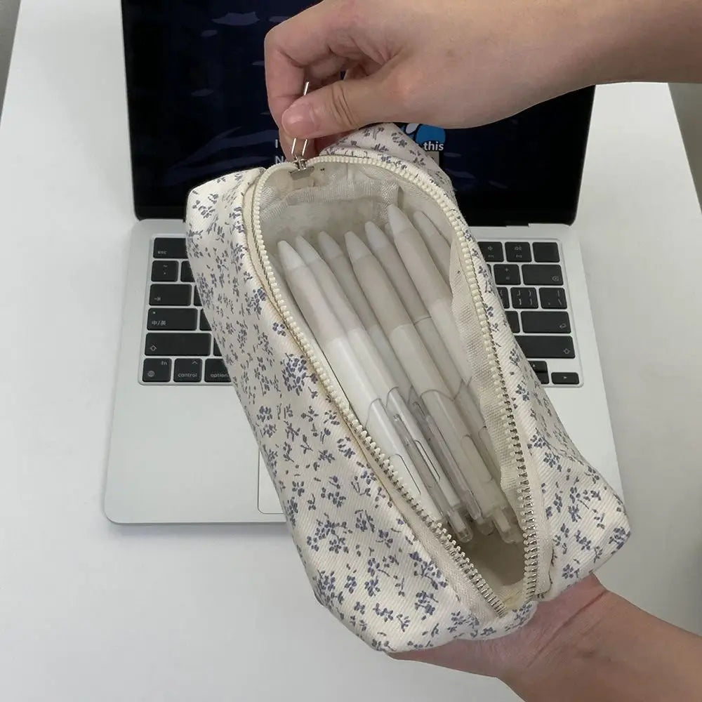 Canvas pencil pouch with zipper, cream base and navy micro-floral print; pens inside