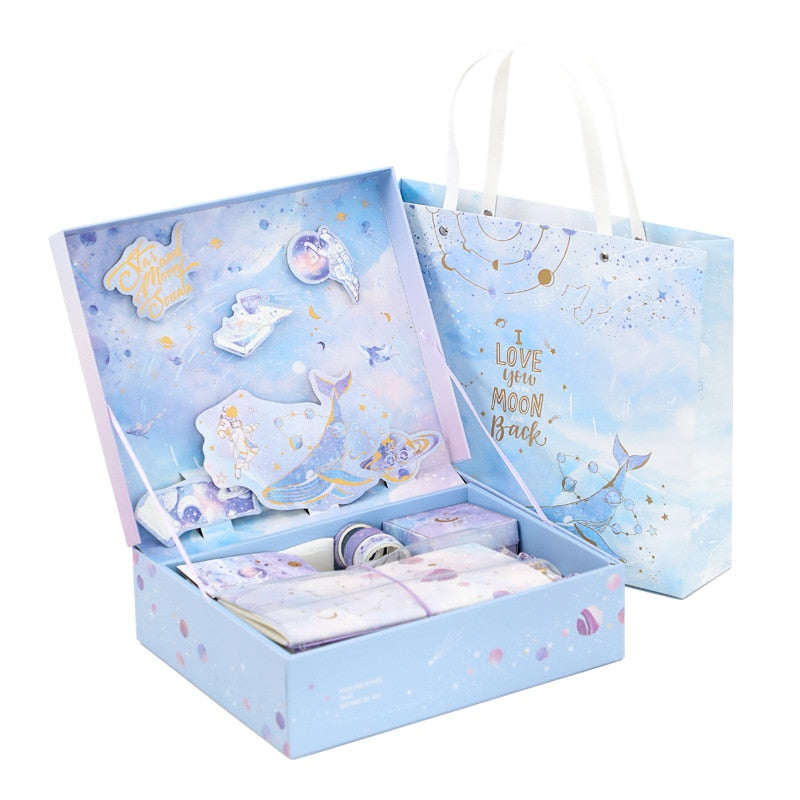 Blue stationery gift set with patterned gift bag and open box holding cards and tape