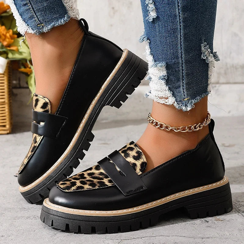 Black platform loafers with leopard print slip panels and two buckle straps.