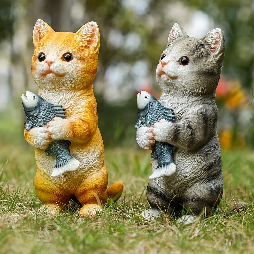 Two cat figurines, orange and gray, each holding a gray fish in its paws