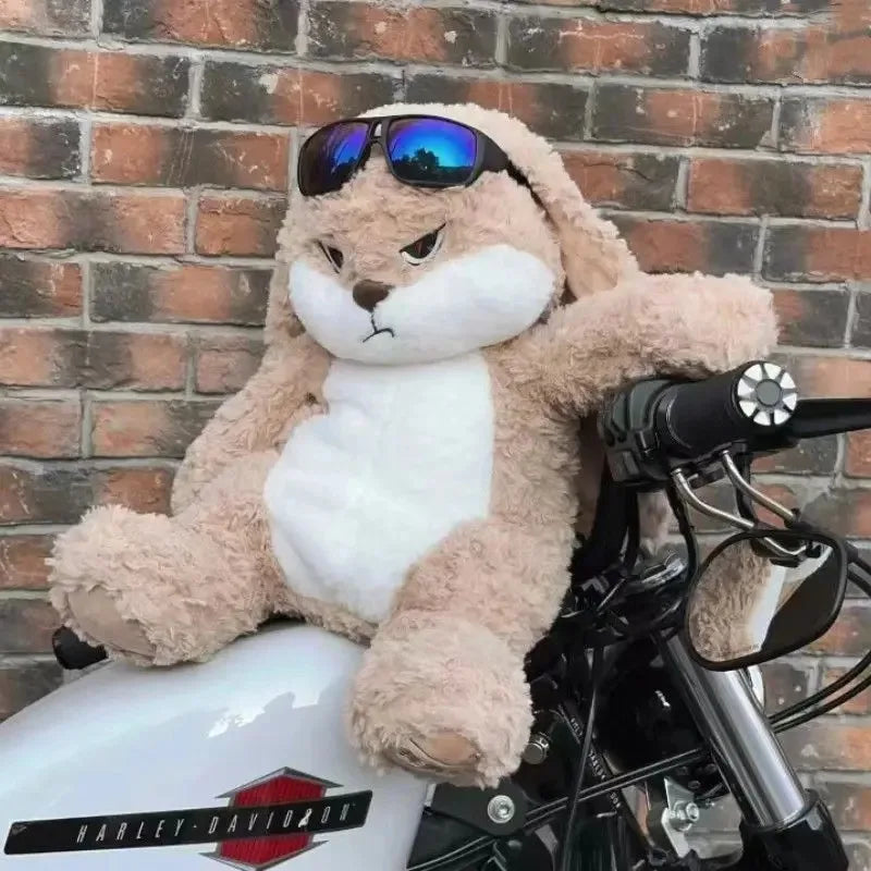 Angry long-eared rabbit plush wearing blue mirrored sunglasses, seated on a couch
