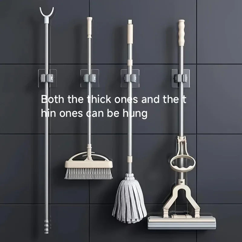 Wall-mounted mop and broom holder clips holding long-handled cleaning tools