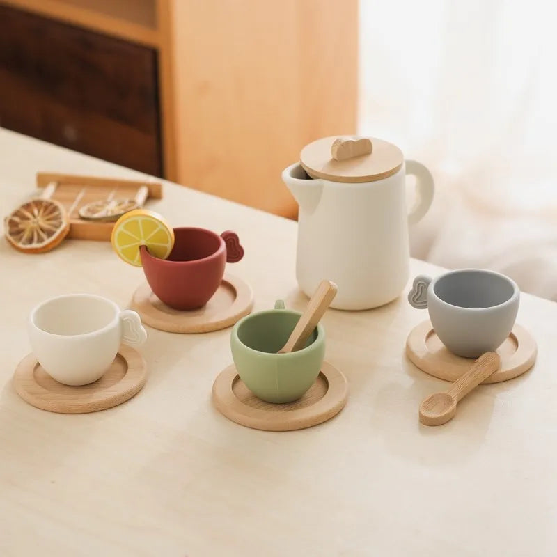 Wooden tea set with white teapot, colorful cups on round tray, and wooden spoon