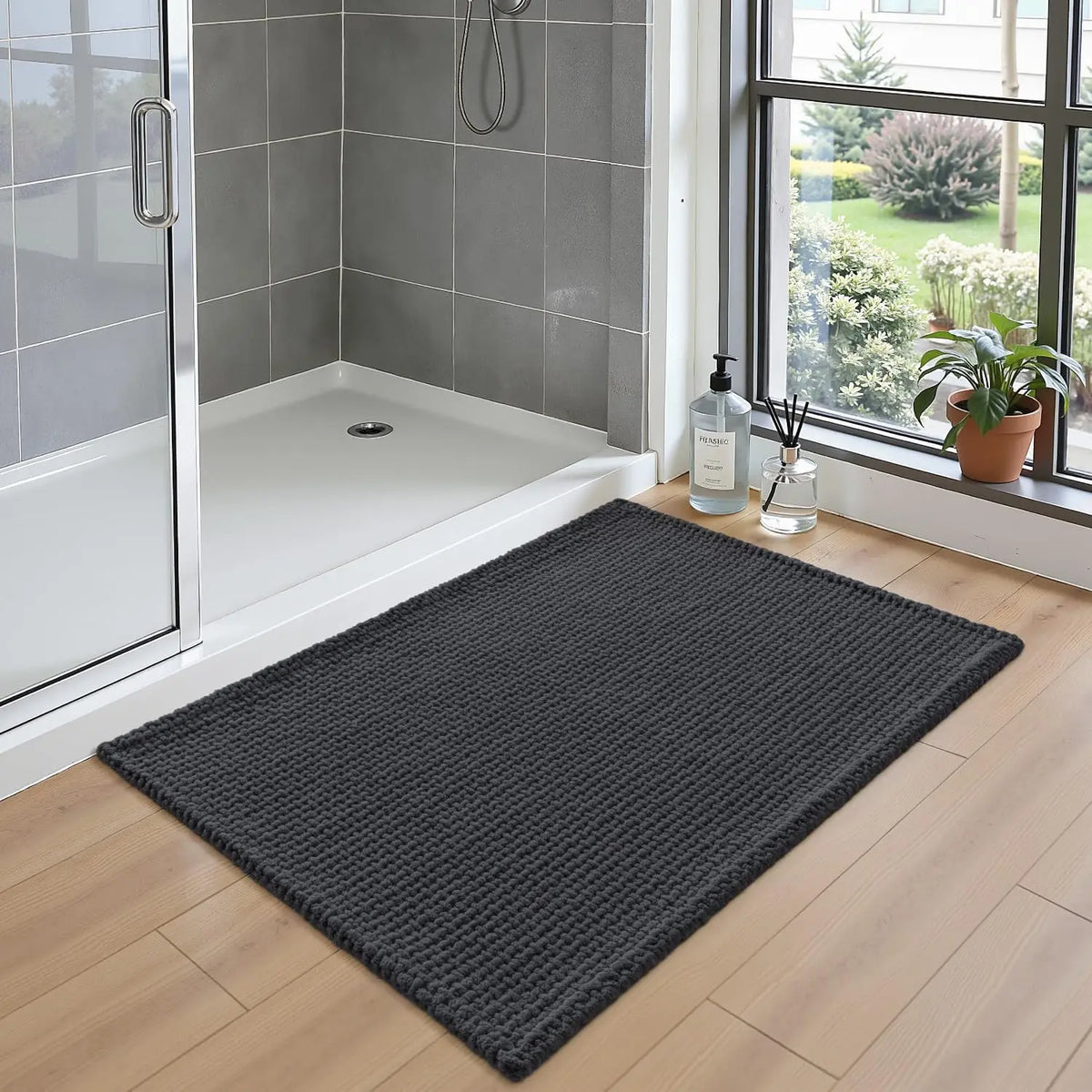 Dark grey chenille bath rug laid on tile floor in shower area