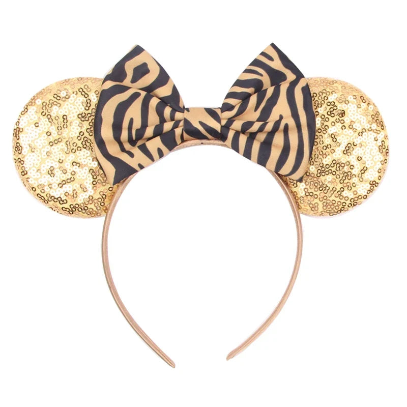 Gold glitter Mickey-style ears headband with zebra-print bow and curved band.