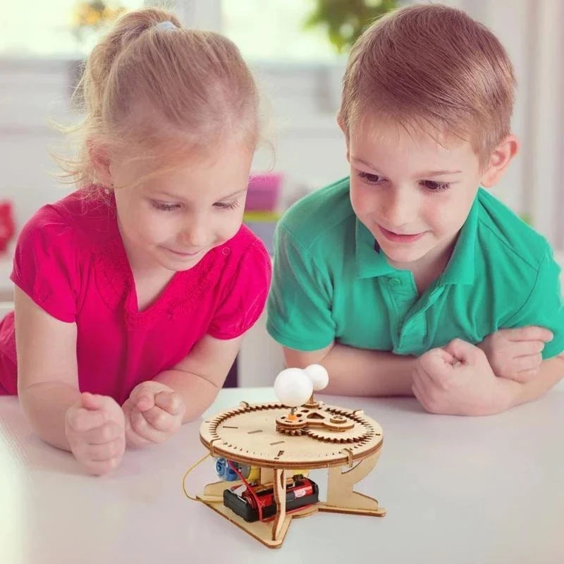 Solar system wooden puzzle kit on white table, kids helping turn the small gears