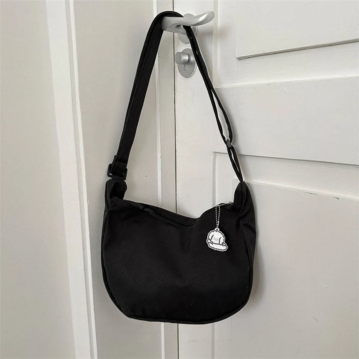 Black crossbody shoulder bag with puppy pendant and adjustable strap, zip-top