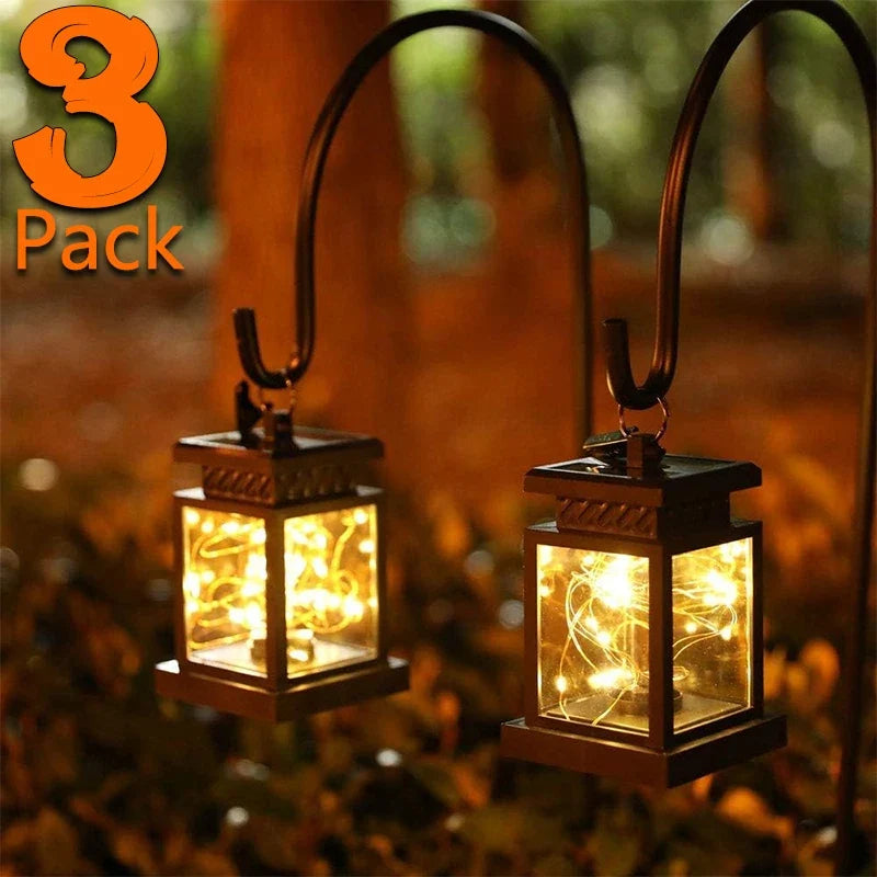 Set of 3 black solar lanterns with arched handles, glowing warm white through glass