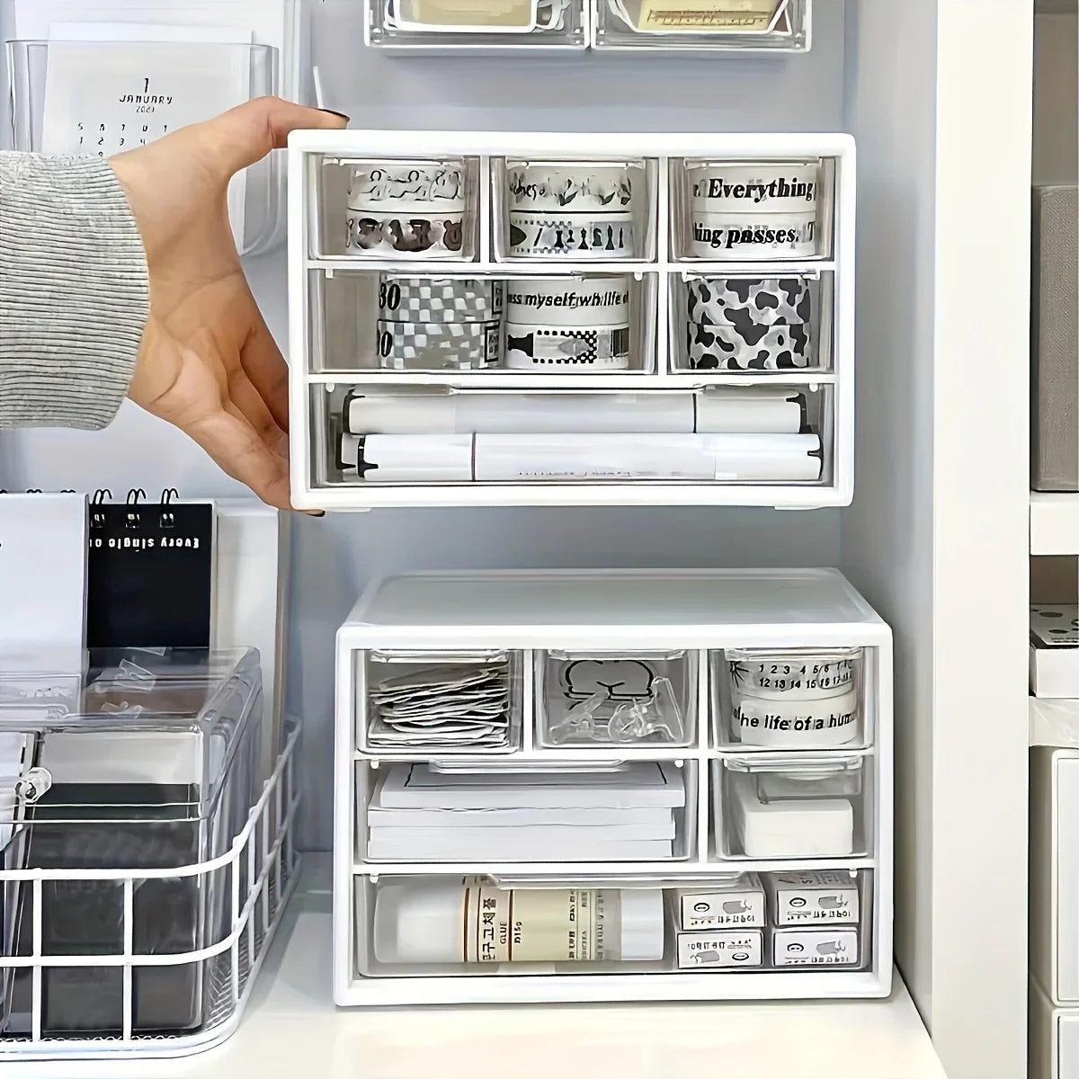 White plastic desk organizer with hand lifting open top drawer and inner storage trays