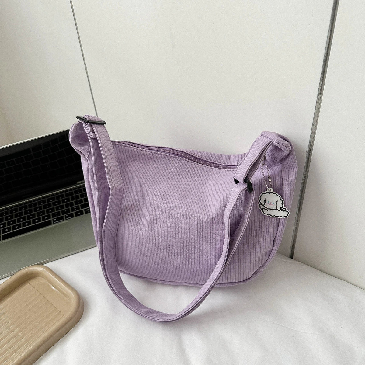 Purple crossbody bag with puppy pendant and adjustable shoulder strap, zip-top