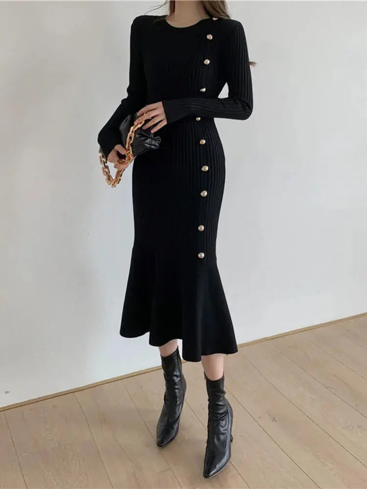 Black ribbed knit sweater dress with long sleeves, gold buttons, and flared midi hem.