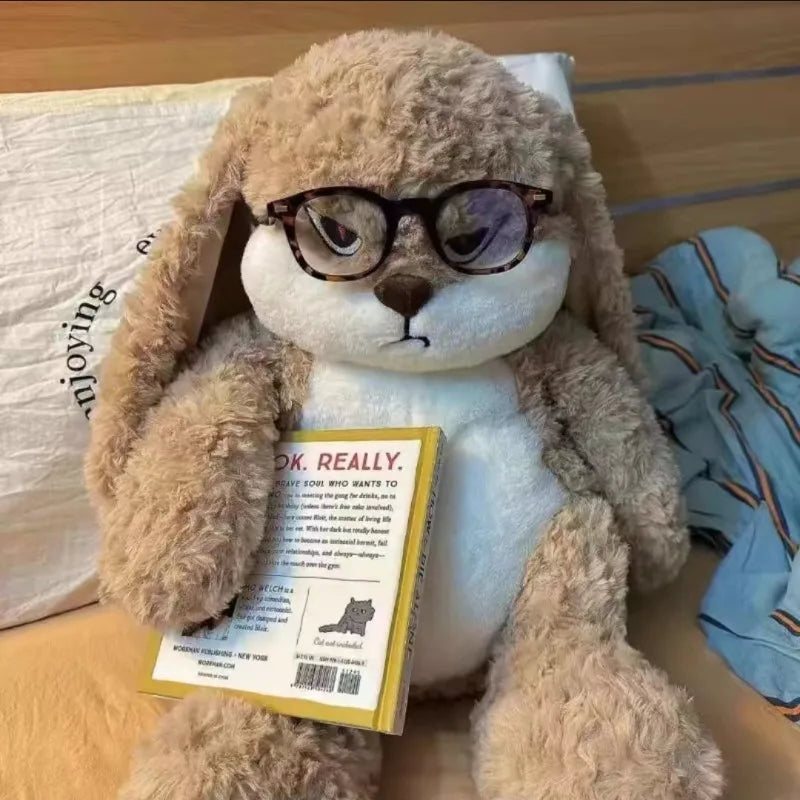 Angry long-eared rabbit plush with round glasses, holding an instruction book