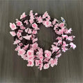Cherry blossom wreath LED lights with pink blossoms on dark rattan ring, warm white