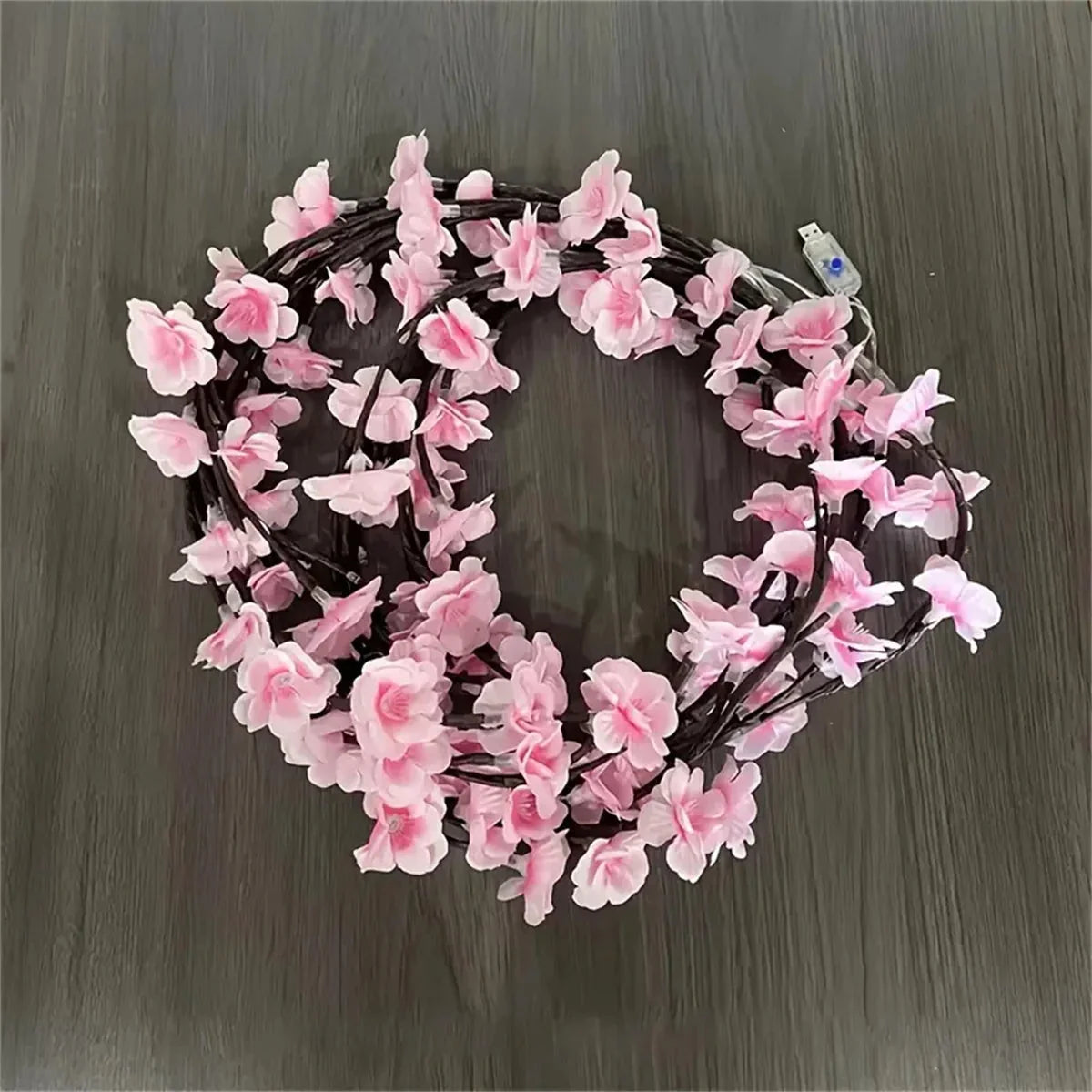 Cherry blossom wreath LED lights with pink blossoms on dark rattan ring, warm white
