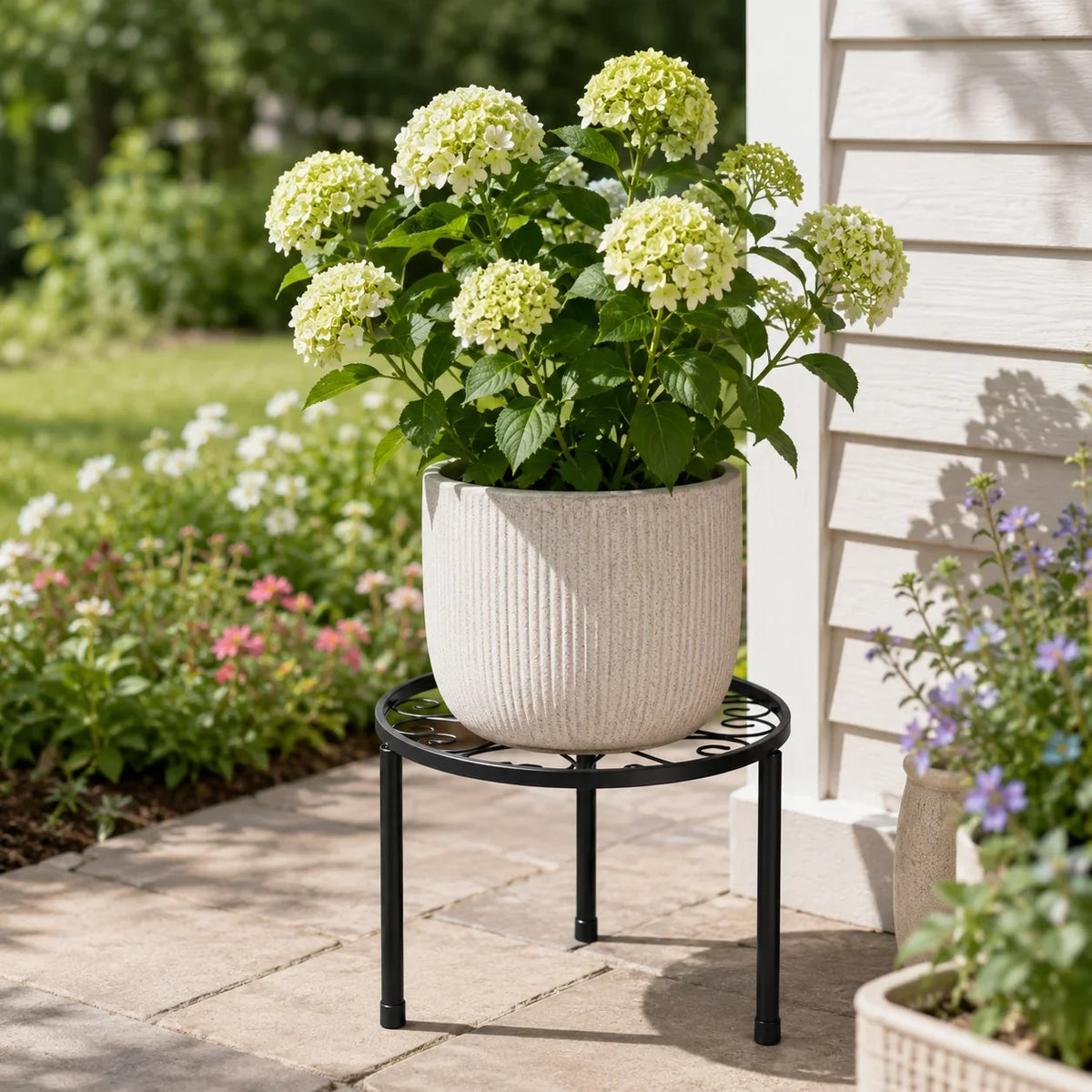 Round black metal plant stand with raised edge and four legs for flower pots