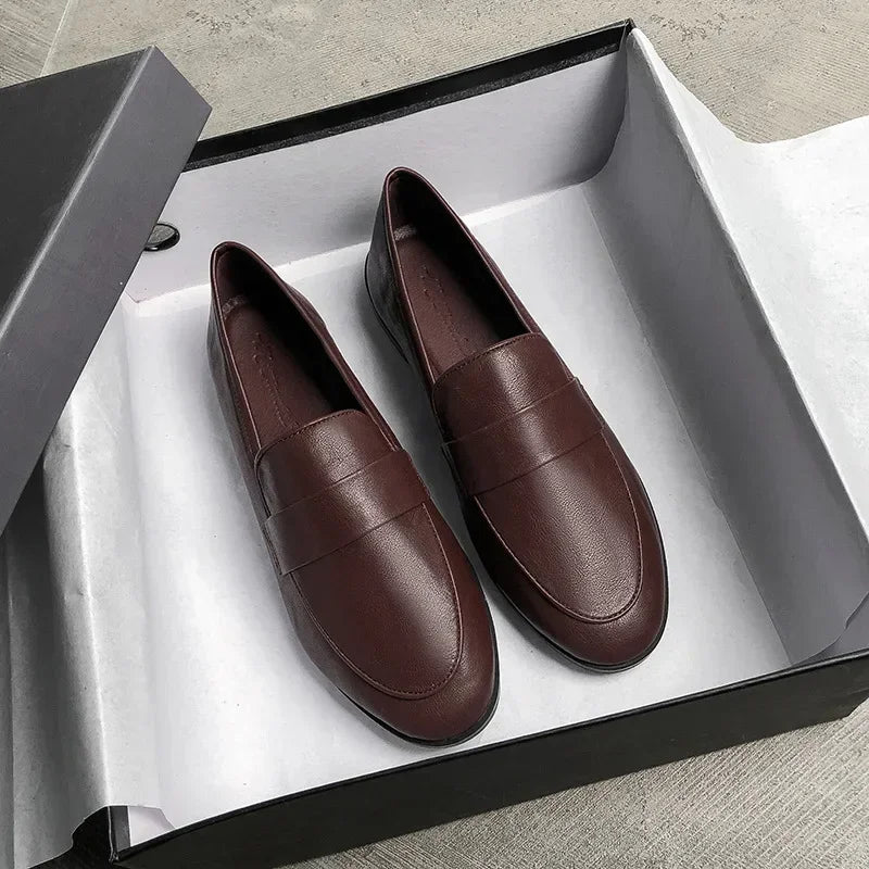 Dark brown slip-on leather loafers, flat design, round toe with stitched apron detail