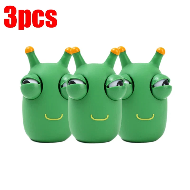 Three green worm squeeze fidget toys lined up, each with pop-out eyes