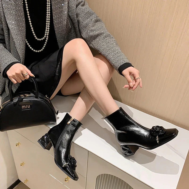 Women’s black ankle boots with square toe, glossy finish, and flower-like toe detail