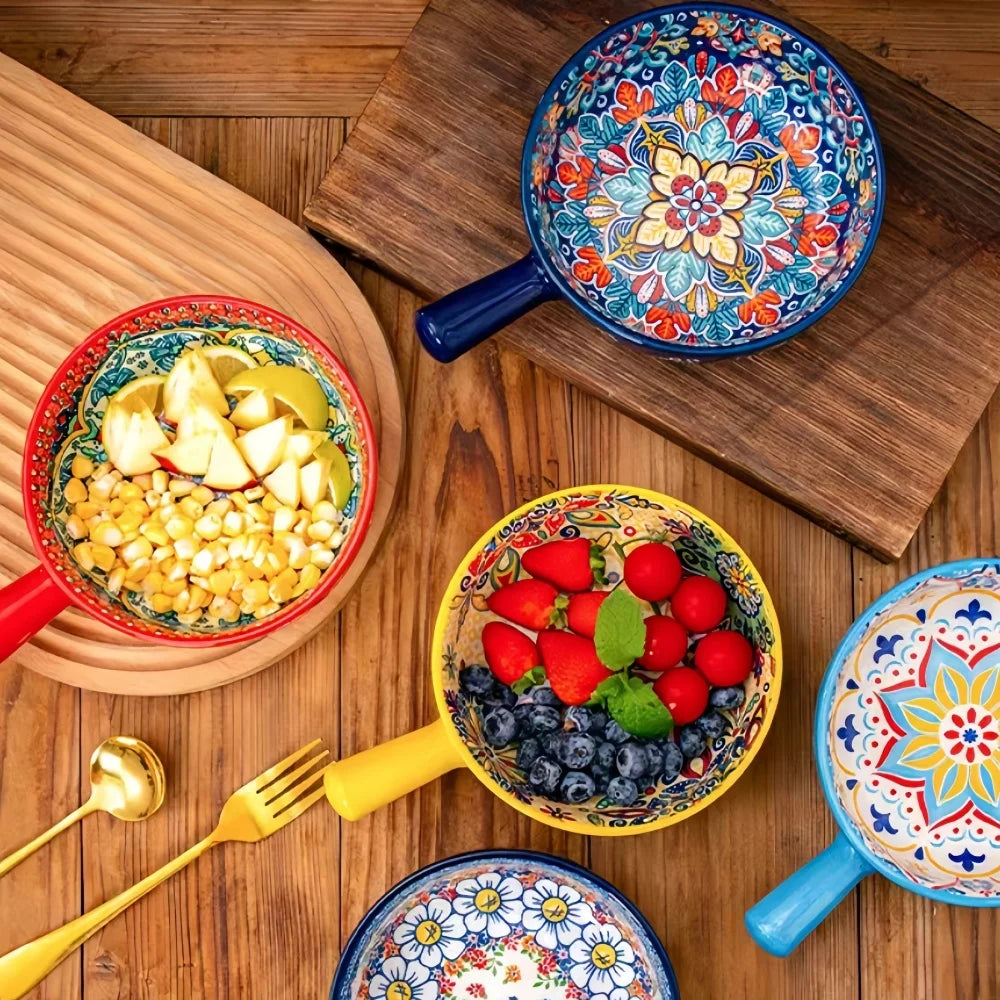 Set of ceramic salad bowls with floral patterns and colored handles on wooden board