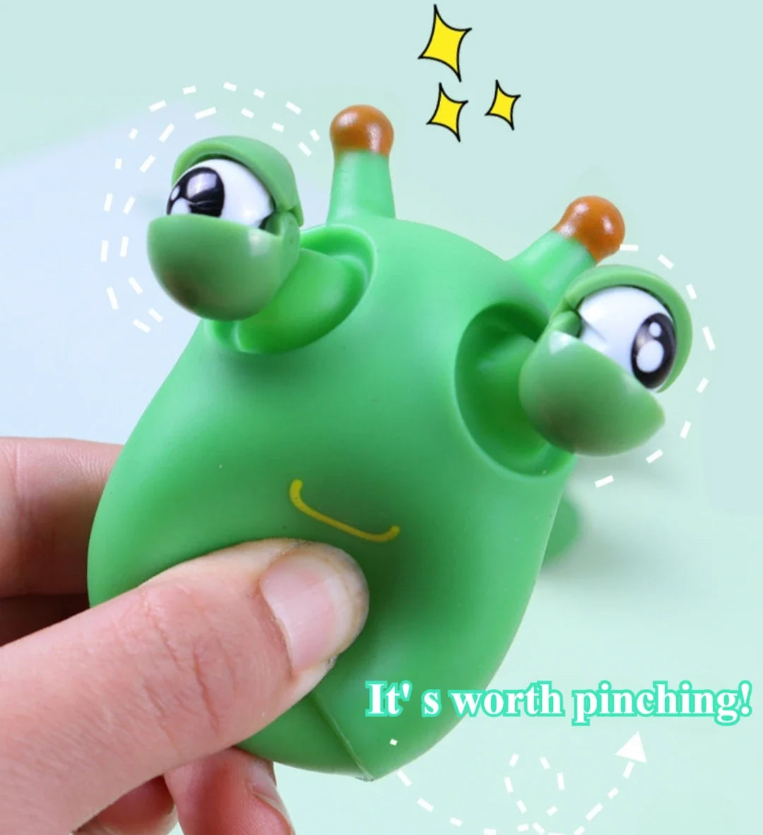 Green worm squeeze fidget toy with pop-out eyes, held between fingers