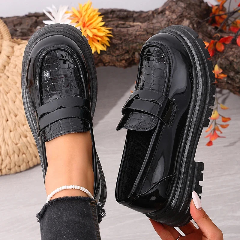 Black patent leather loafers with round toe, front strap, and thick tread platform sole