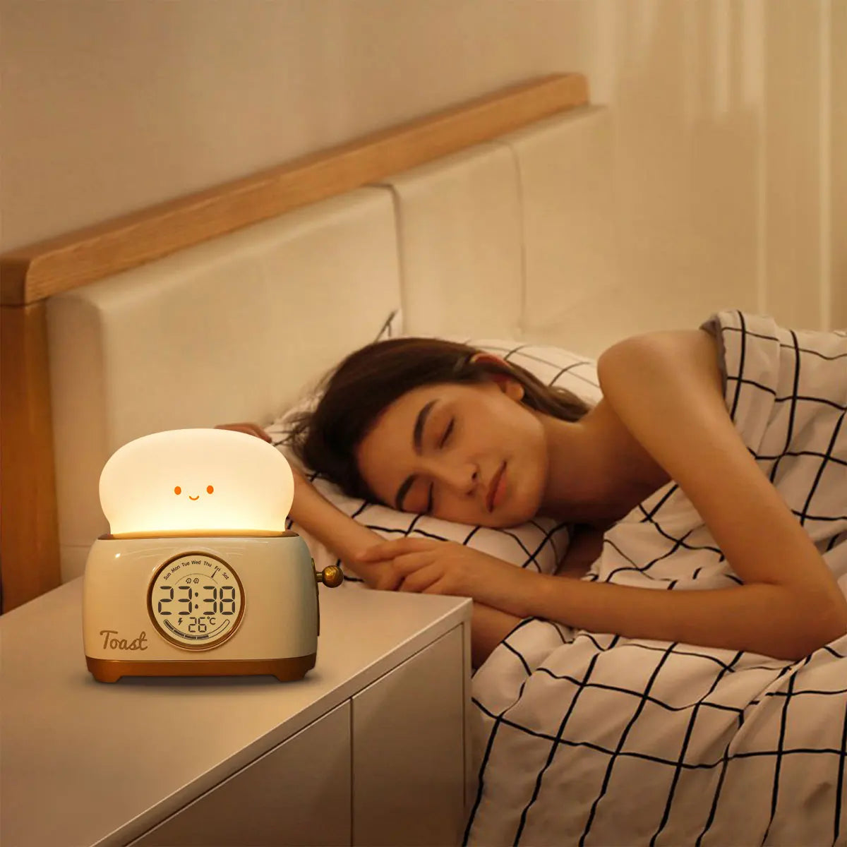 Toaster night light alarm clock glowing on bedside table near a sleeping child