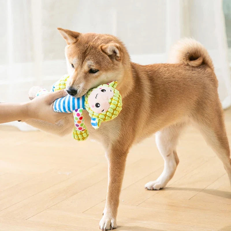 Plush bug dog toy with striped arms and smiling face held in a dog’s mouth