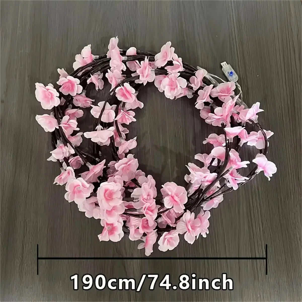 Cherry blossom wreath-style LED lights with pink blossoms on dark rattan ring, warm white