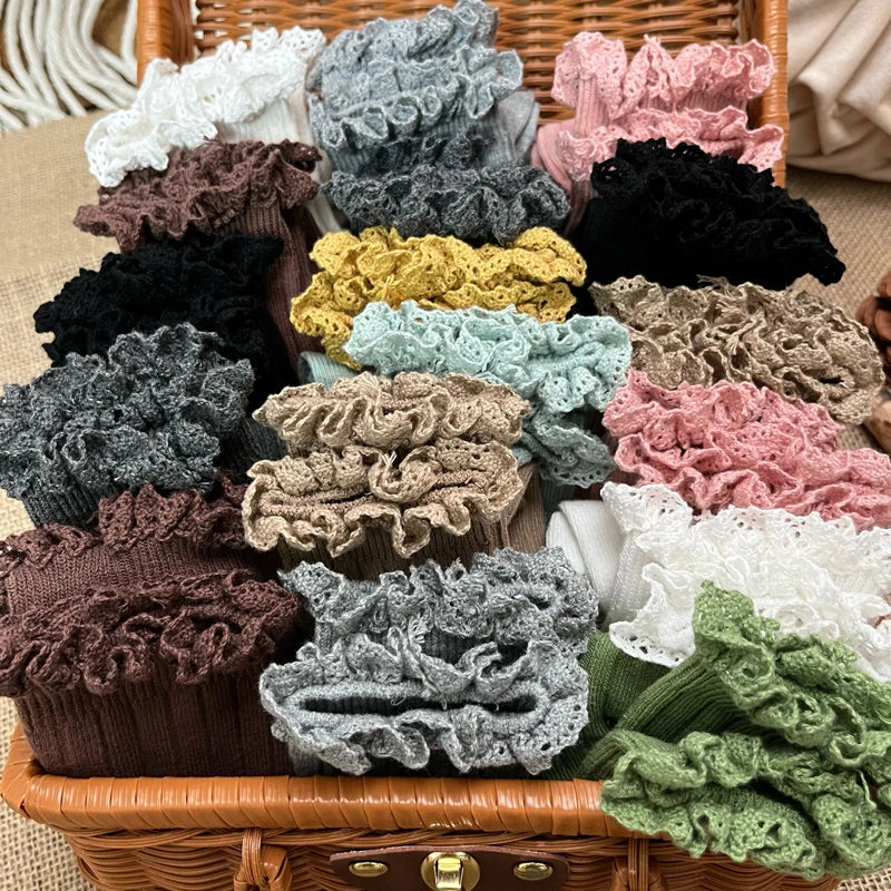 Assorted knee-high ruffle socks with lace cuffs, mixed colors in a woven basket