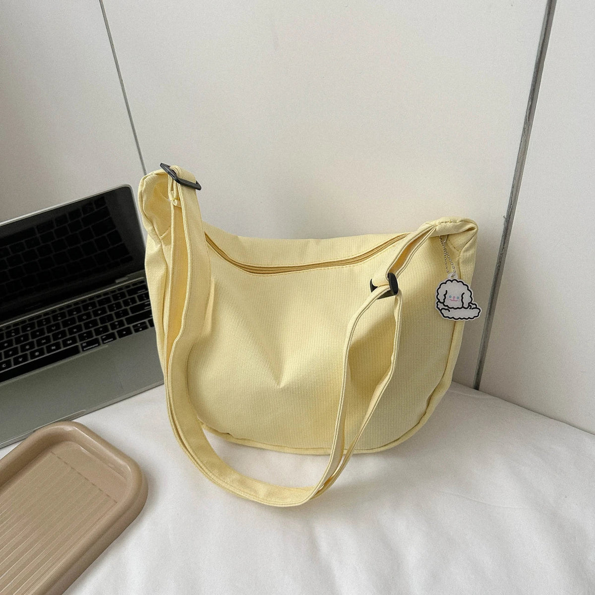 Yellow crossbody bag with puppy pendant, zip-top, and adjustable shoulder strap