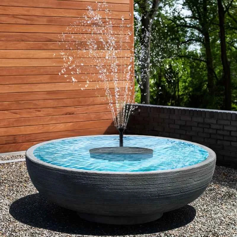 Solar fountain pump with nozzle spraying water from a round outdoor pond