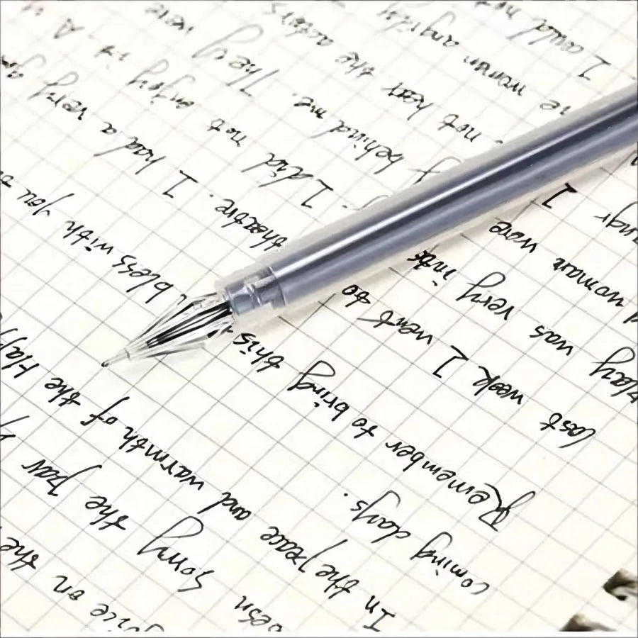 Close-up of a clear-barrel diamond tip gel pen writing on grid notebook