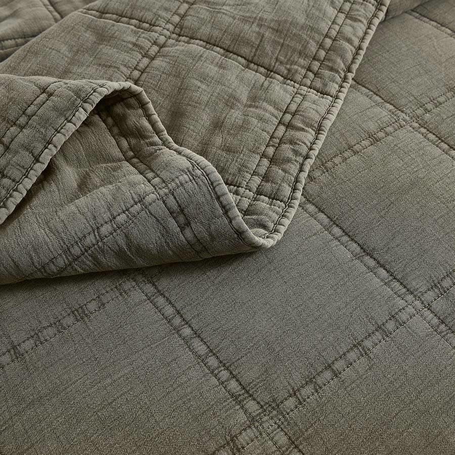 Stone-washed cotton quilt texture in sage green with stitched grid pattern