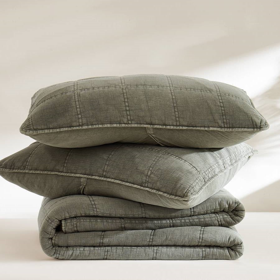 Stacked sage green quilt set with decorative stitching and soft washed texture
