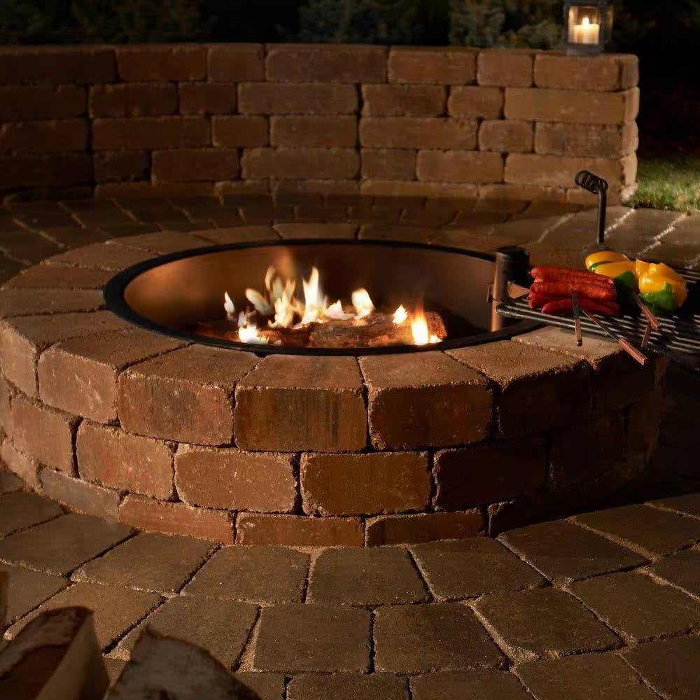 Round concrete block fire pit with open flame and cooking grill grate