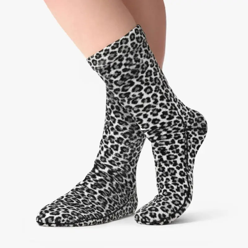 Snow leopard fleece socks worn on feet, tall crew style, black-and-white print.