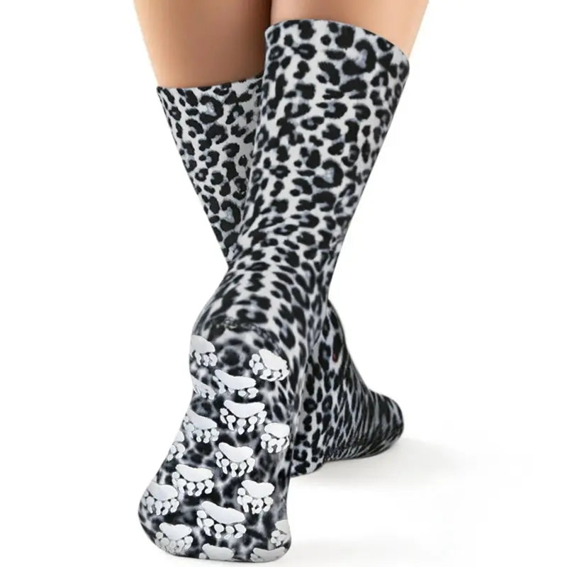 Snow leopard fleece socks on feet, black-and-white leopard-print design.