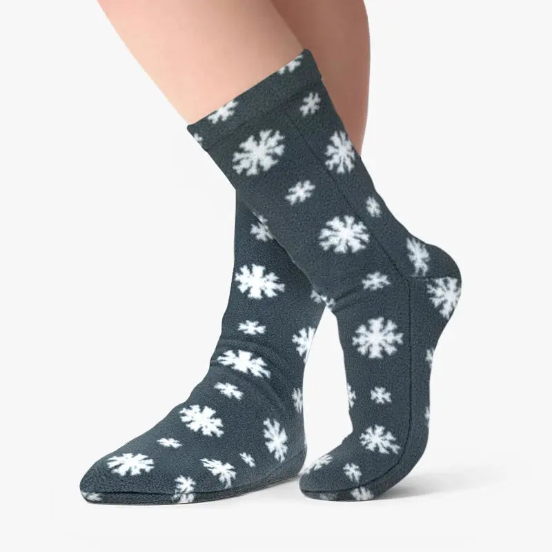 Dark gray fleece socks with white snowflakes, worn on model legs