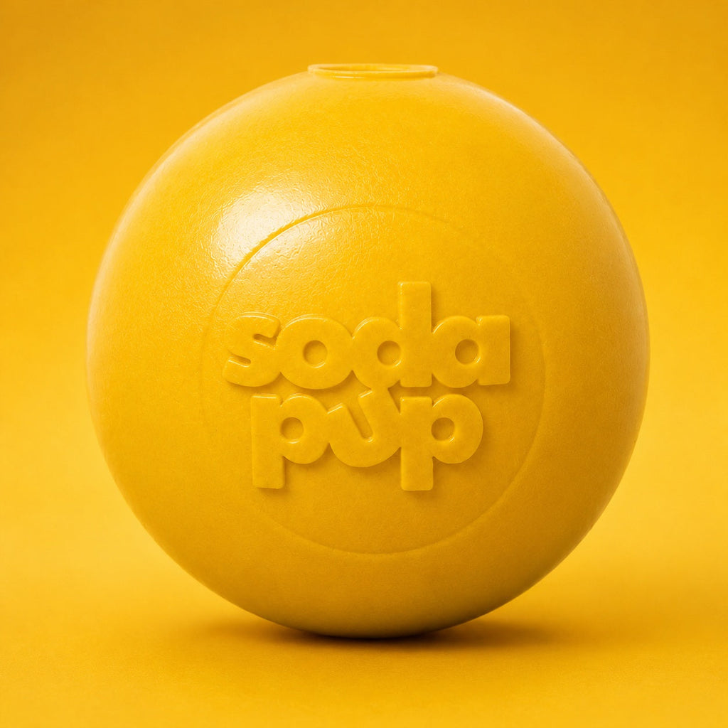 Yellow squeaky dog ball close-up with Soda Pup embossed logo