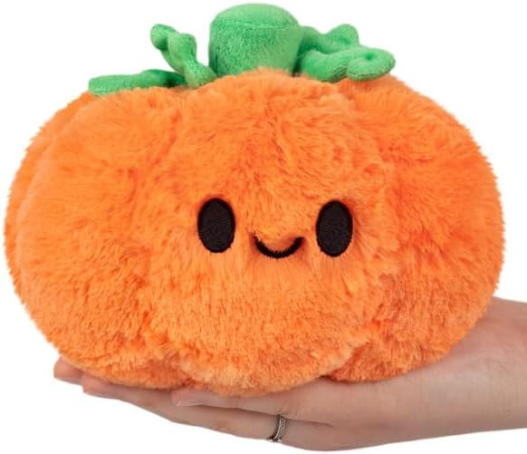 Orange plush pumpkin toy with cute smiling face, green leaves, held by hand