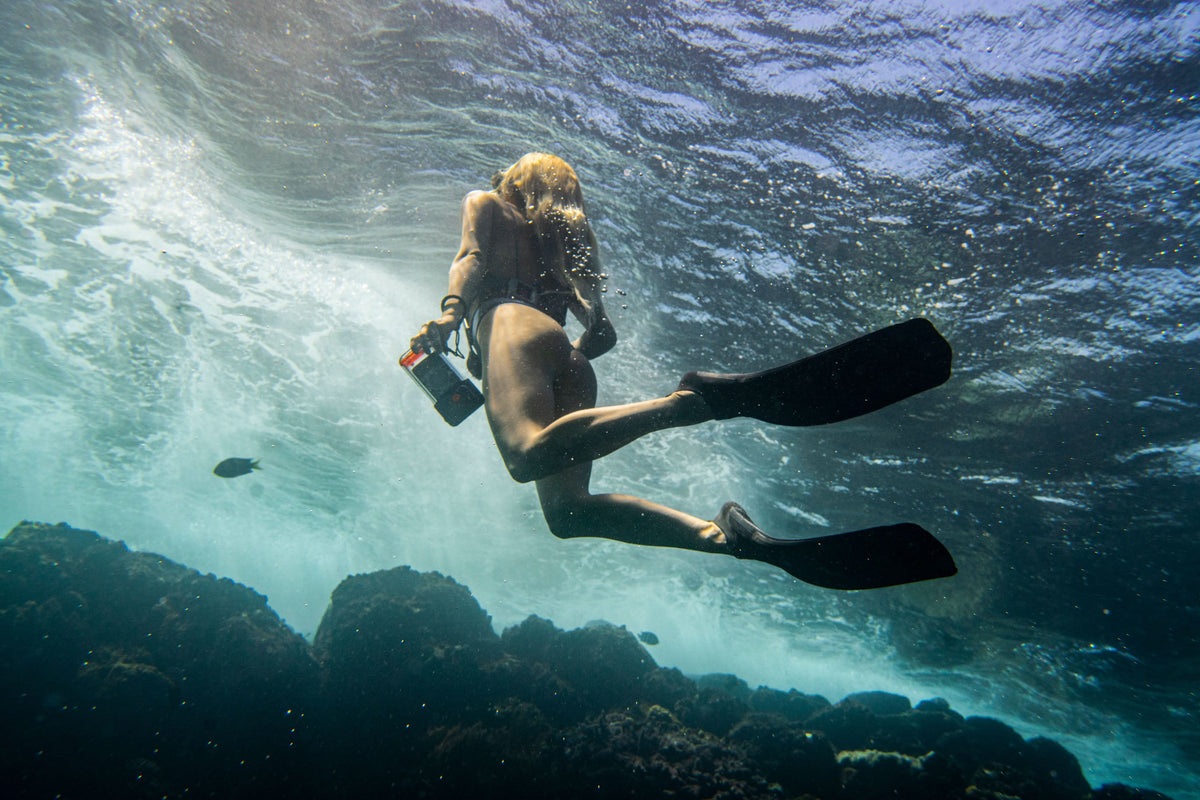 Waterproof phone case held underwater, with a phone inside a clear front window.