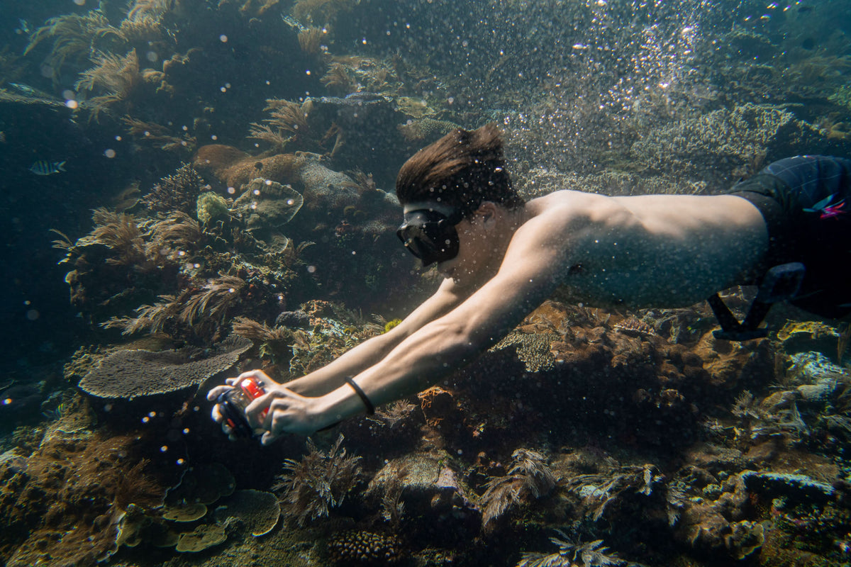 Waterproof phone case with clear cover in hand underwater, phone screen visible.