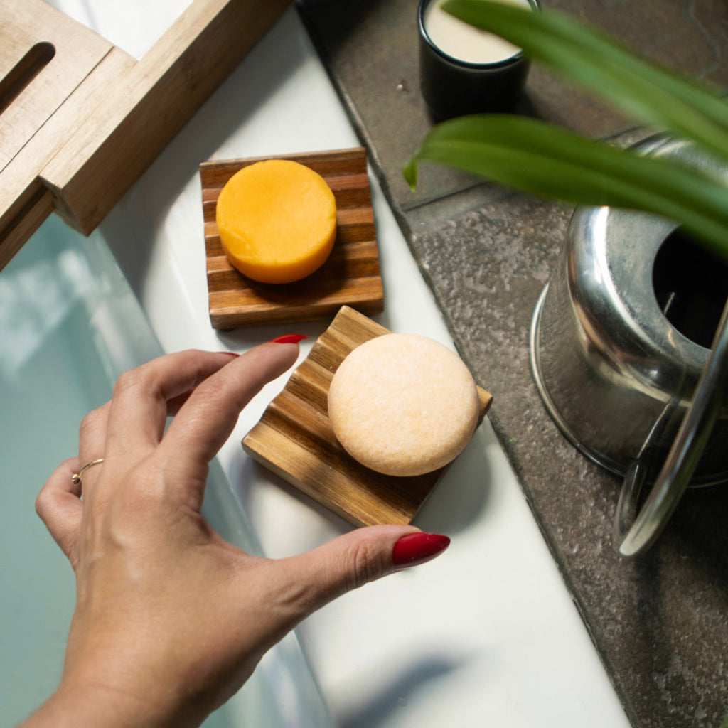 Moisturizing shampoo bar and sliced rounds on a wooden tray near a second bar