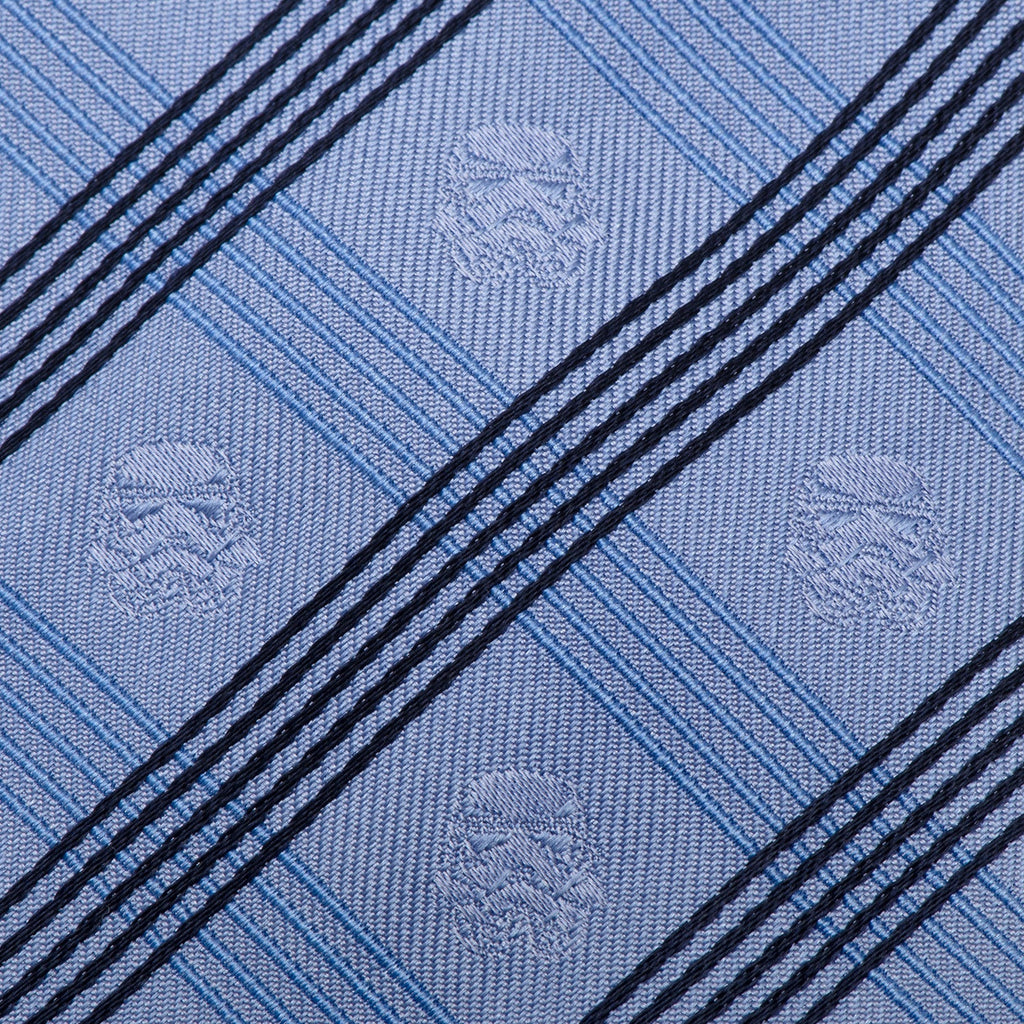 Close-up of light blue plaid necktie fabric with diagonal dark stripes and emblems