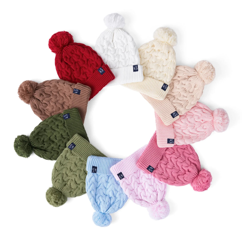 Sage green cable-knit pom beanie in a circle of assorted pom beanies