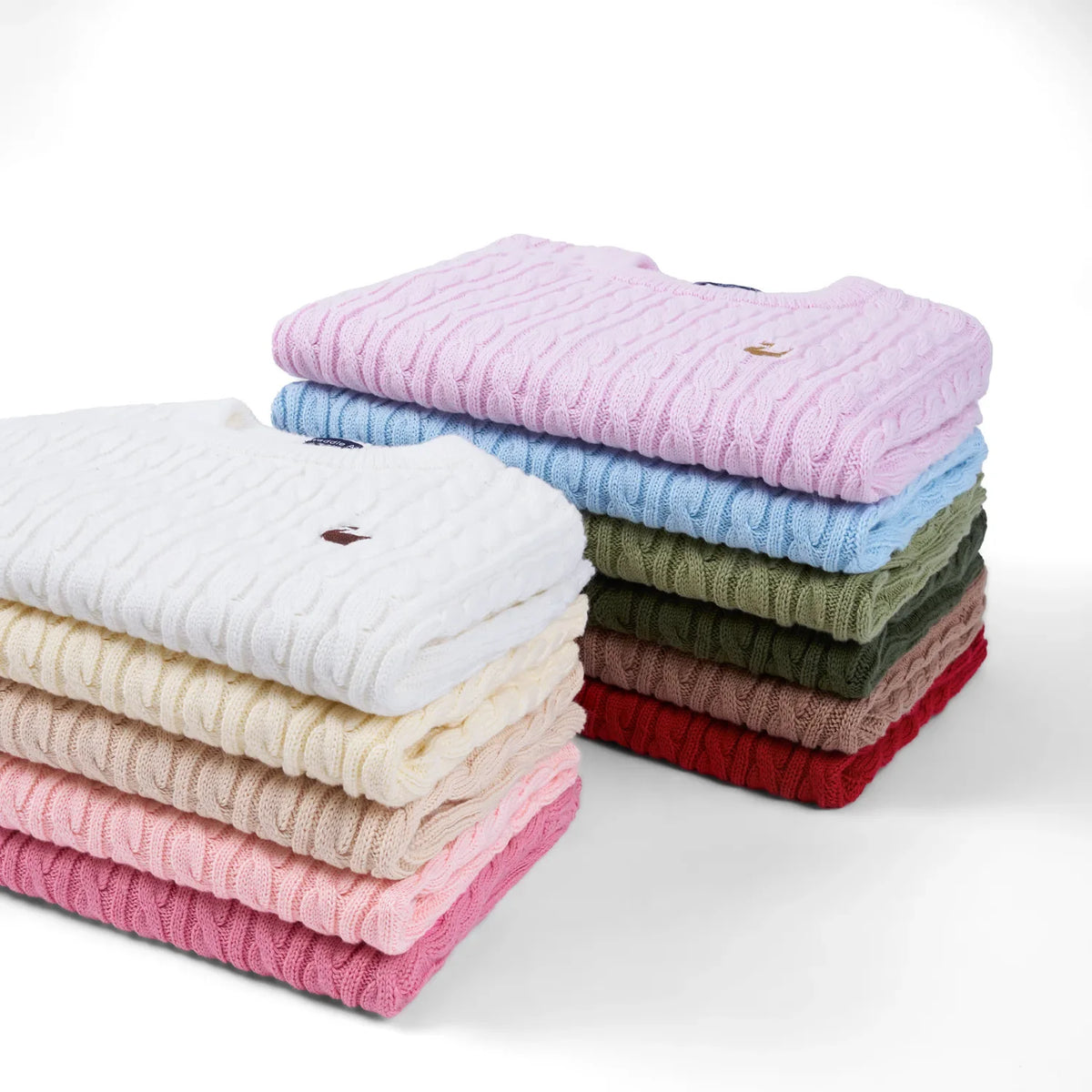 Stack of folded baby cable-knit sweaters in assorted colors