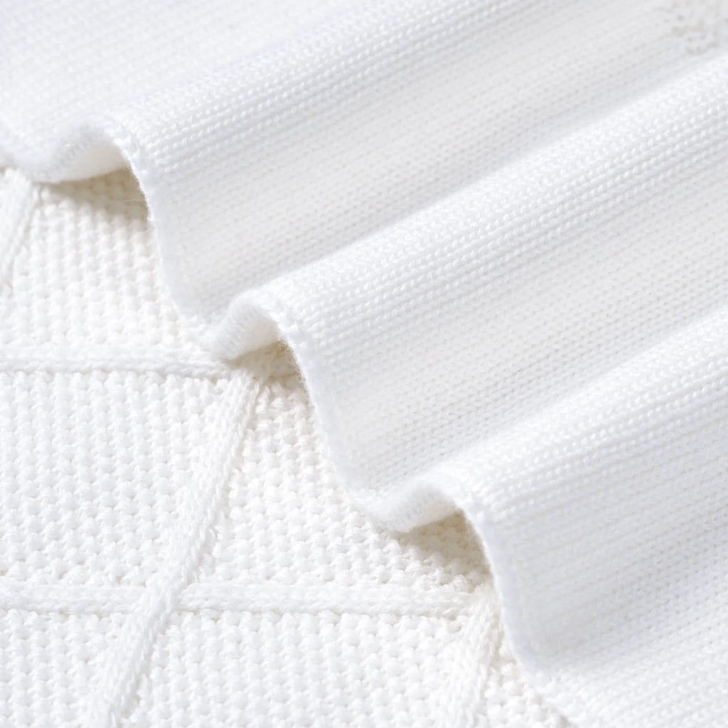 Close-up of white knit diamond-stitch blanket with textured seam detail
