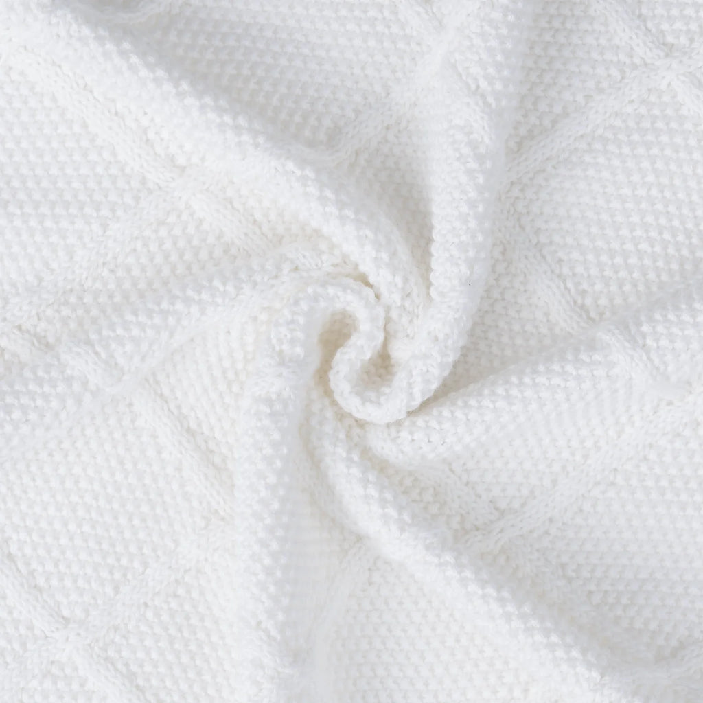 Close-up of white knit baby blanket corner with soft woven texture