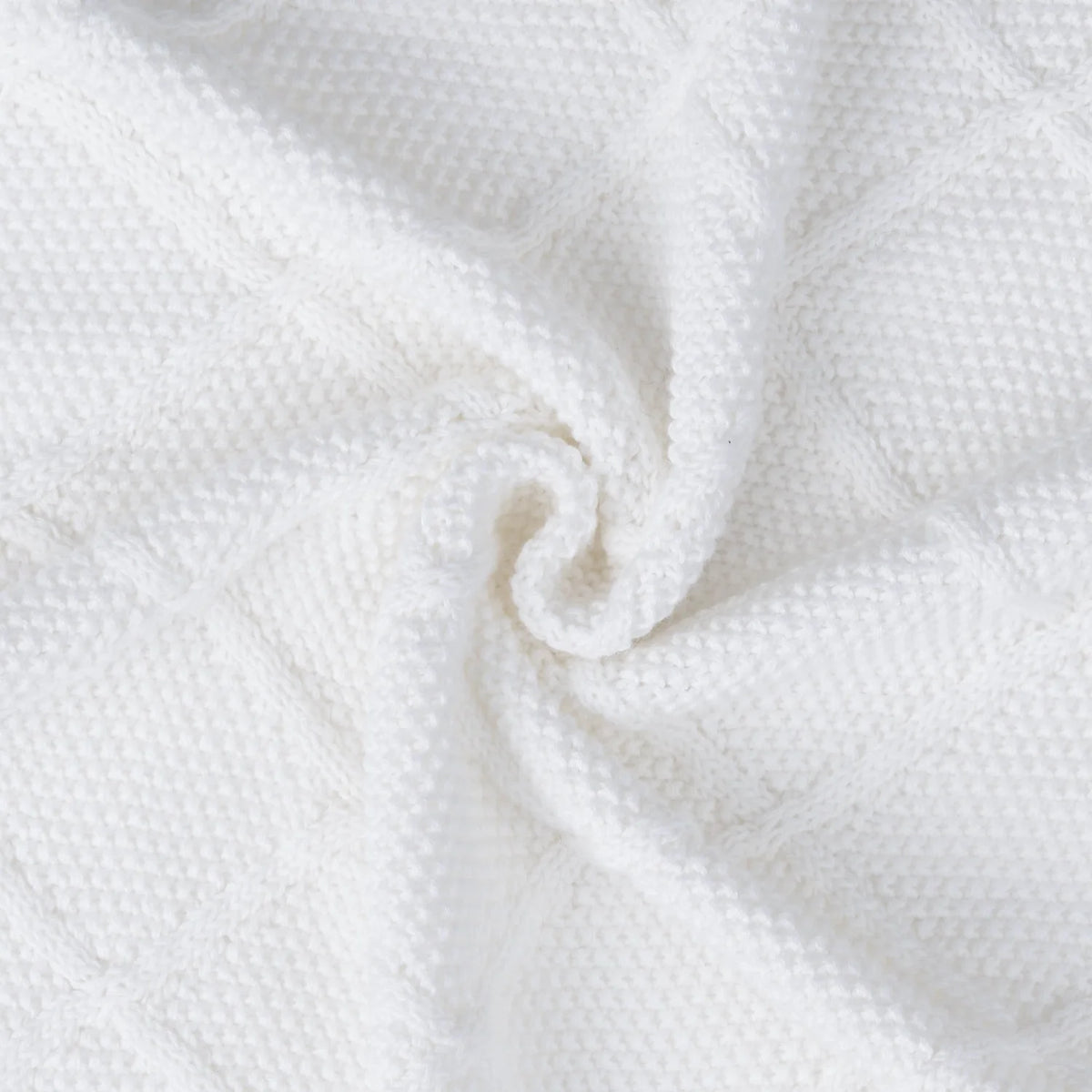 Close-up of white knit baby blanket corner with soft woven texture