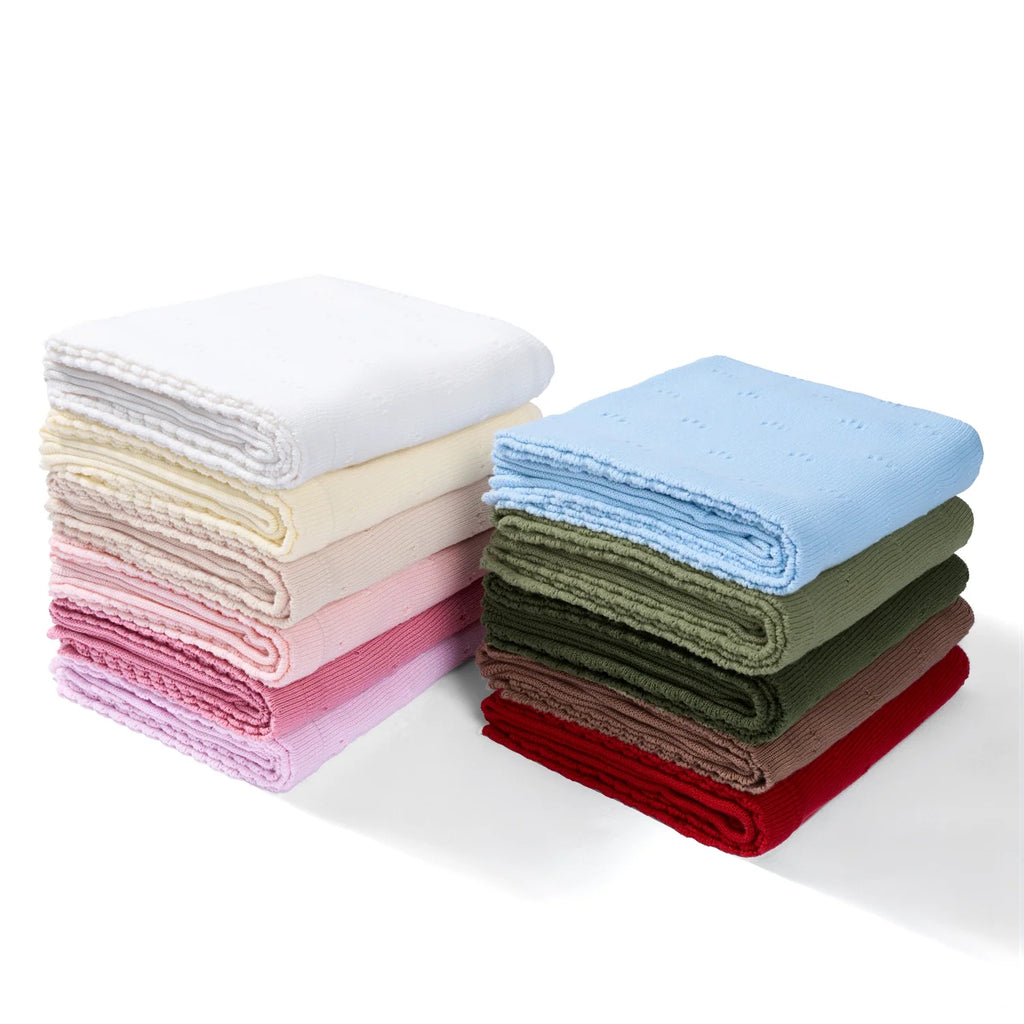 Pointelle baby knit blanket stack in assorted colors, folded blankets with textured eyelet pattern.